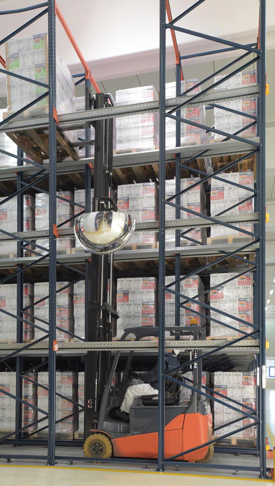 I carrelli elevatori percorrono l’interno dello scaffale drive-in con il carico sollevato sopra al livello in cui verrà depositato